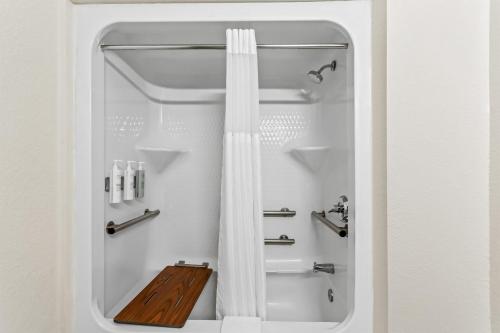 a bathroom with a shower with a white shower curtain at Spark by Hilton La Grange in La Grange