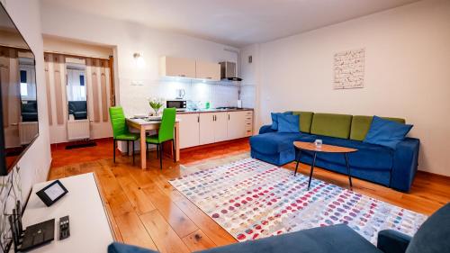 a living room with a blue couch and a kitchen at Park Sportowy, Sun & Snow in Krynica Zdrój