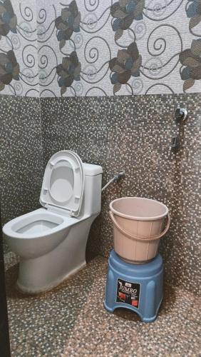 ein Badezimmer mit Toilette und einem Eimer auf einer Waage in der Unterkunft Gitanshi Palace in Ayodhya