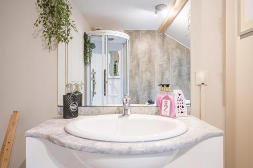 Un baño con un lavabo blanco y un espejo. en Maison Jarrier, en Saint-Jean-de-Maurienne