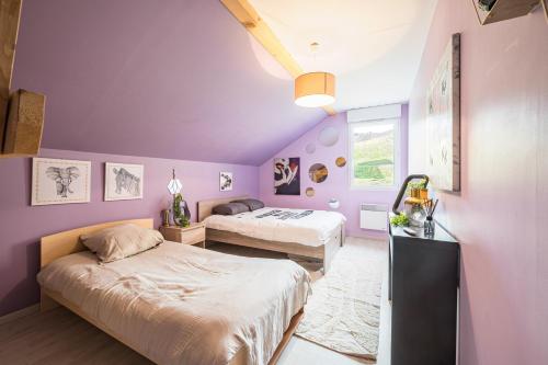 Dos camas en una habitación con paredes moradas. en Maison Jarrier, en Saint-Jean-de-Maurienne