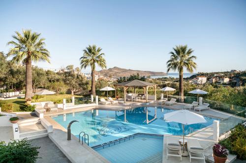 una piscina con sedie, ombrelloni e palme di Villa Life ad Agia Marina Nea Kydonias