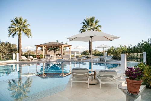 una piscina con sedie, tavolo e ombrellone di Villa Life ad Agia Marina Nea Kydonias