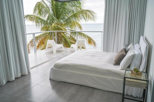Villa Mariposa Ocean Front Mansion with Infinity Pool في غانيكا: غرفة نوم بسرير ابيض و نخلة