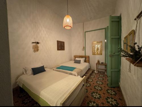 a bedroom with two beds and a pendant light at Hostal Prana in Abejorral