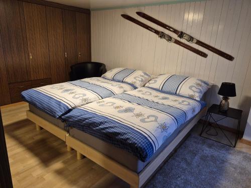 ein Bett mit einer blau-weißen Bettdecke in einem Schlafzimmer in der Unterkunft Chez Berni in Andermatt