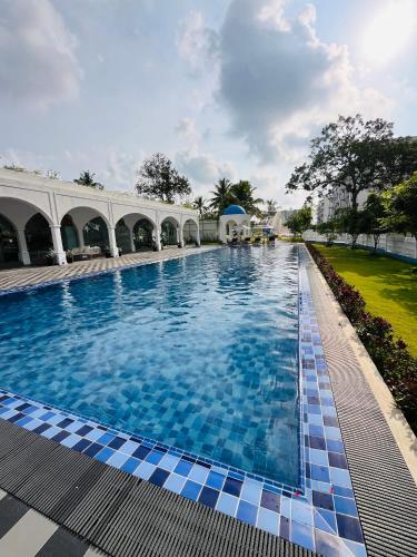 a large swimming pool in a building with blue tiles at Celestial Negombo Pool View Resort Apartments in Negombo