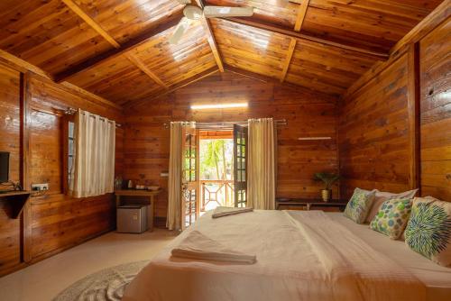 a bedroom with a bed with wooden walls and a ceiling at BOHOA Beach Resort Palolem in Palolem