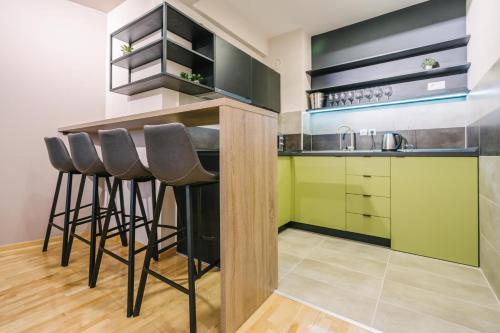 a kitchen with black and green cabinets and stools at NAR Royalton Apartment #60 in Niš