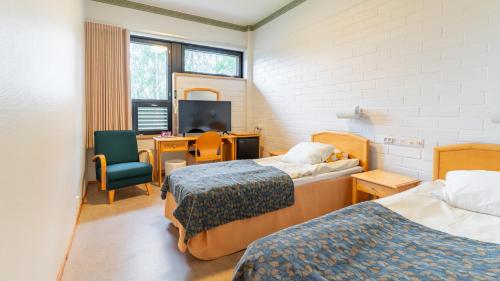 a room with two beds and a desk and a television at Lehmirannan Lomakeskus in Salo