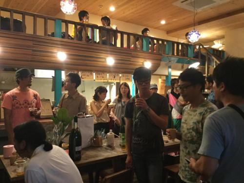 a group of people standing around a bar at The Pax Hostel in Osaka