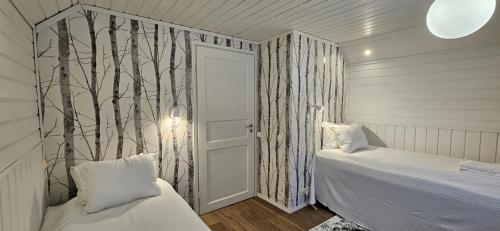 una camera da letto con due letti e una porta con alberi sul muro di Petsukka Levi a Levi
