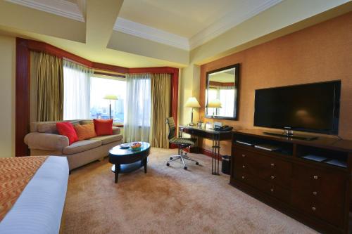 a hotel room with a bed and a flat screen tv at Diamond Hotel Philippines in Manila