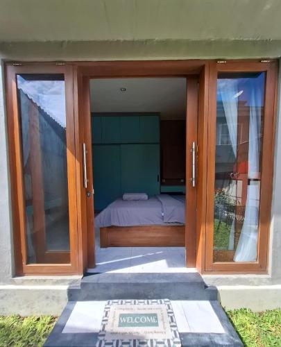 a bedroom with sliding glass doors with a bed inside at Bumbab House by Pigeon in Nusa Dua