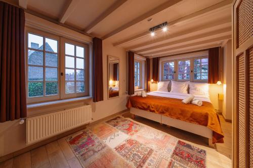 a bedroom with a bed and two windows at B&B Barabas in Bruges