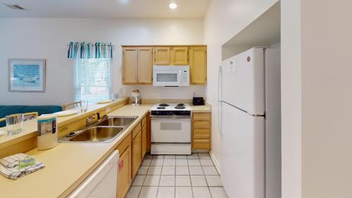 a kitchen with a white refrigerator and a sink at Club Villas Unit 17D - Lower Level in Sunset Beach