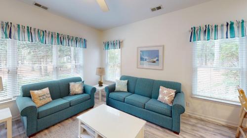a living room with two blue couches and windows at Club Villas Unit 17D - Lower Level in Sunset Beach