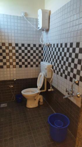 a bathroom with a toilet in a checkered wall at Hotel Tulip Inn & Lodging in Viravdi