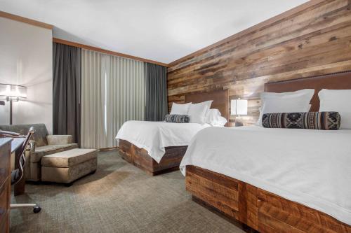 a hotel room with two beds and a chair at Norfolk Lodge & Suites, an Ascend Collection Hotel in Norfolk