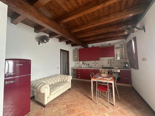 cocina con armarios rojos, mesa y sofá en Tenute Pacelli - Azienda Agricola, en Malvito