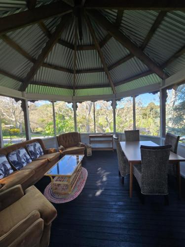 a living room with couches and tables in a pavilion at Nottingham way Homestay in Blackwood