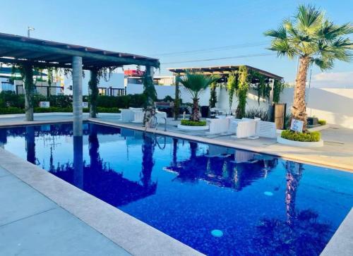 a pool at a resort with palm trees and chairs at New ground floor apartment, very comfortable and excellent location in Mazatlán