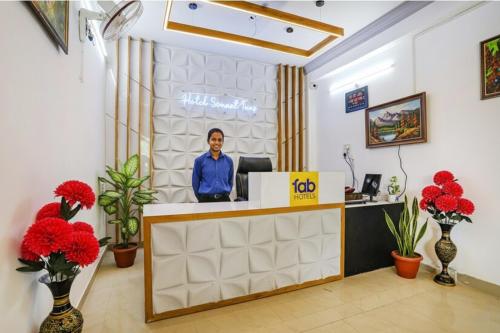 a woman standing at a reception desk in a room with red flowers at FabHotel Sonnet Inns in Rānchī