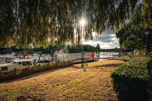 a tree hanging over a field with boats in a marina at Cabane 3 étoiles - ccbechc in Neuilly-sur-Marne