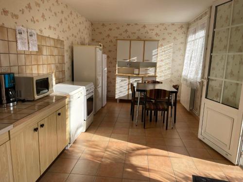 a kitchen with a table and a white refrigerator at Domaine de la Chambre in Verrières