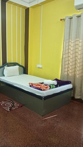 a bed in a room with a yellow wall at Trishan Hotel in Dhupguri