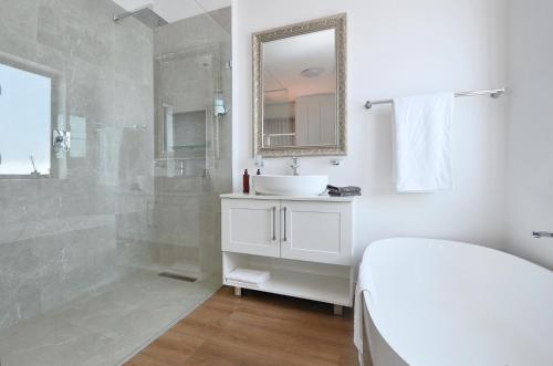 a white bathroom with a sink and a shower at Caracal 54 in Yzerfontein