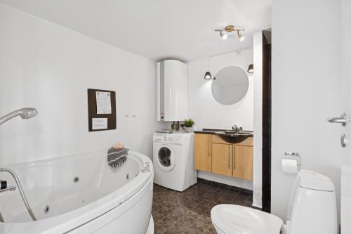 Feriehus 3007 في Nørre Lyngvig: حمام مع حوض استحمام وغسالة ملابس