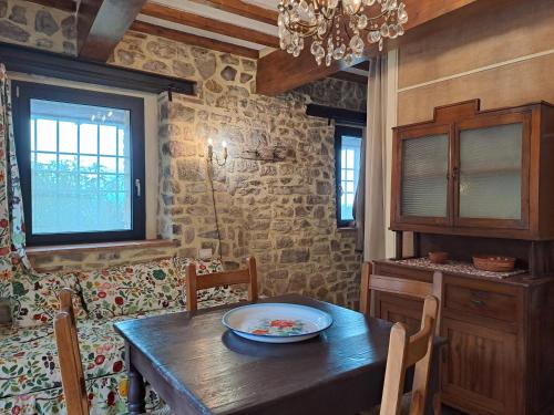 Rustico La Tinaia في Montigiano: غرفة طعام مع طاولة خشبية وجدار حجري