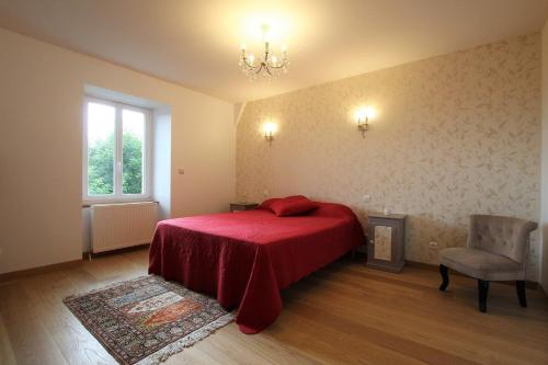 una camera da letto con un letto rosso e una sedia di Chambre Romantique, Le Suc du Pommier a Grazac