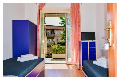 a room with two beds and a sliding glass door at La Dolce Sosta in Lido di Ostia