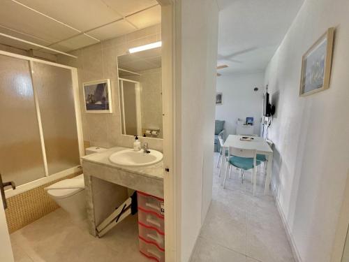 a bathroom with a sink and a toilet and a table at Forcat - Apartamento con jardín y piscina in Ciutadella