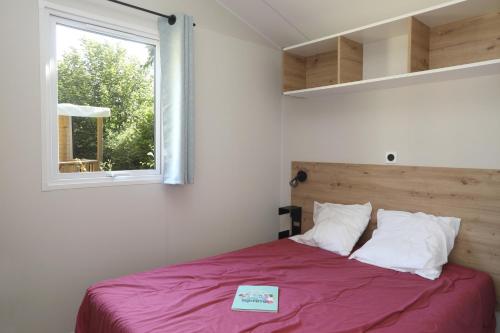 a small bedroom with a bed with a window at Camping Le Val de Trie in Béhen