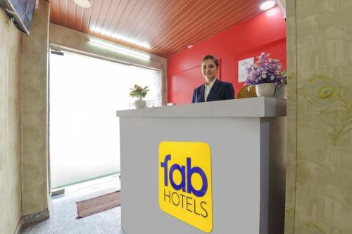FabHotel Silver Stay 02 في جايبور: رجل يقف عند مكتب الاستقبال مع لافتة فنادق عايدة