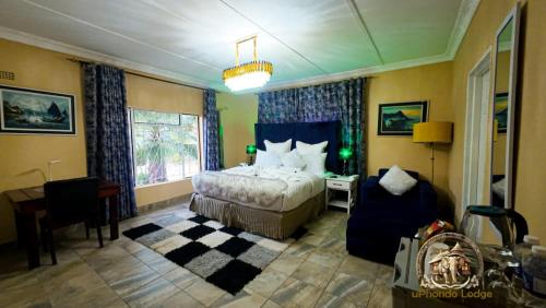 a bedroom with a bed and a desk and a chair at uPhondo Lodge in Bulawayo