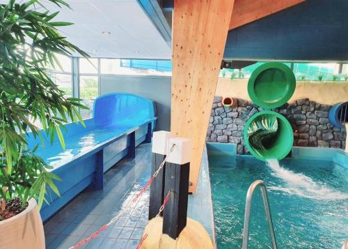 a pool with a water slide in a house at Welcome in - Beachhouse Renesse 2645 aan de duinen - Camping Julianahoeve in Renesse