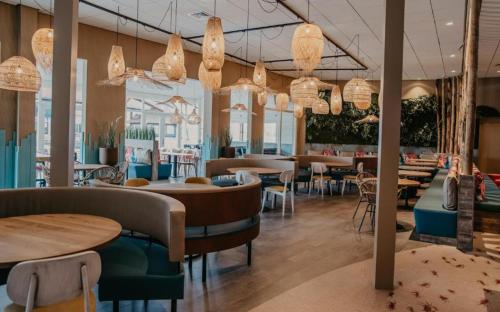 a restaurant with tables and chairs and chandeliers at Welcome in - Beachhouse Renesse 2645 aan de duinen - Camping Julianahoeve in Renesse