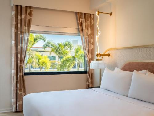 1 dormitorio con 1 cama y una ventana con palmeras en The Luce, St. Pete Beach, a Tribute Portfolio Hotel, en St Pete Beach