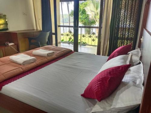 a bed with red and white pillows in a room at BharathaPuzha Resort in Kārakkād