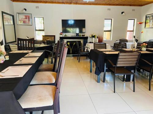 een eetkamer met tafels en stoelen en een open haard bij Palm Leaf – Hazeldene Kwekwe with pool - 2333 in Kwekwe