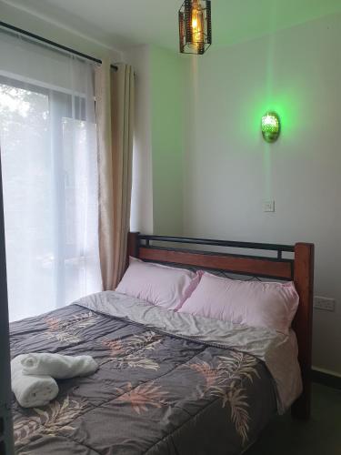 a bedroom with a bed with a window and a bedspread at TSAVO Room 202 in Kiambu