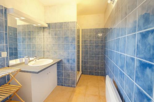 Un baño con paredes de azulejos azules y un lavabo. en Villa la Baume, en Quinson
