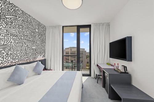 a hotel room with a bed and a tv at Nest Hotel, Aljada in Sharjah