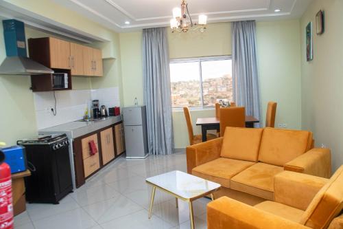 a living room with a couch and a kitchen at Résidence Romacy, appartement 2 chambres avec balcon à Ahala, quartier résidentiel de Yaoundé in Yaoundé