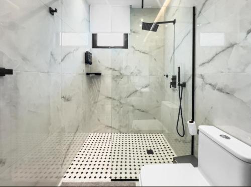 a white bathroom with a shower and a toilet at Hyde Park 6 Couples Retreat Apt With Jacuzzi in San Juan