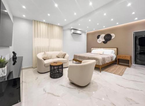a bedroom with a bed and a couch and chairs at Hyde Park 6 Couples Retreat Apt With Jacuzzi in San Juan